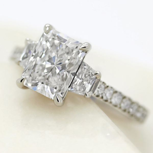 radiant cut diamond with diamond trapezoid side stones engagement ring